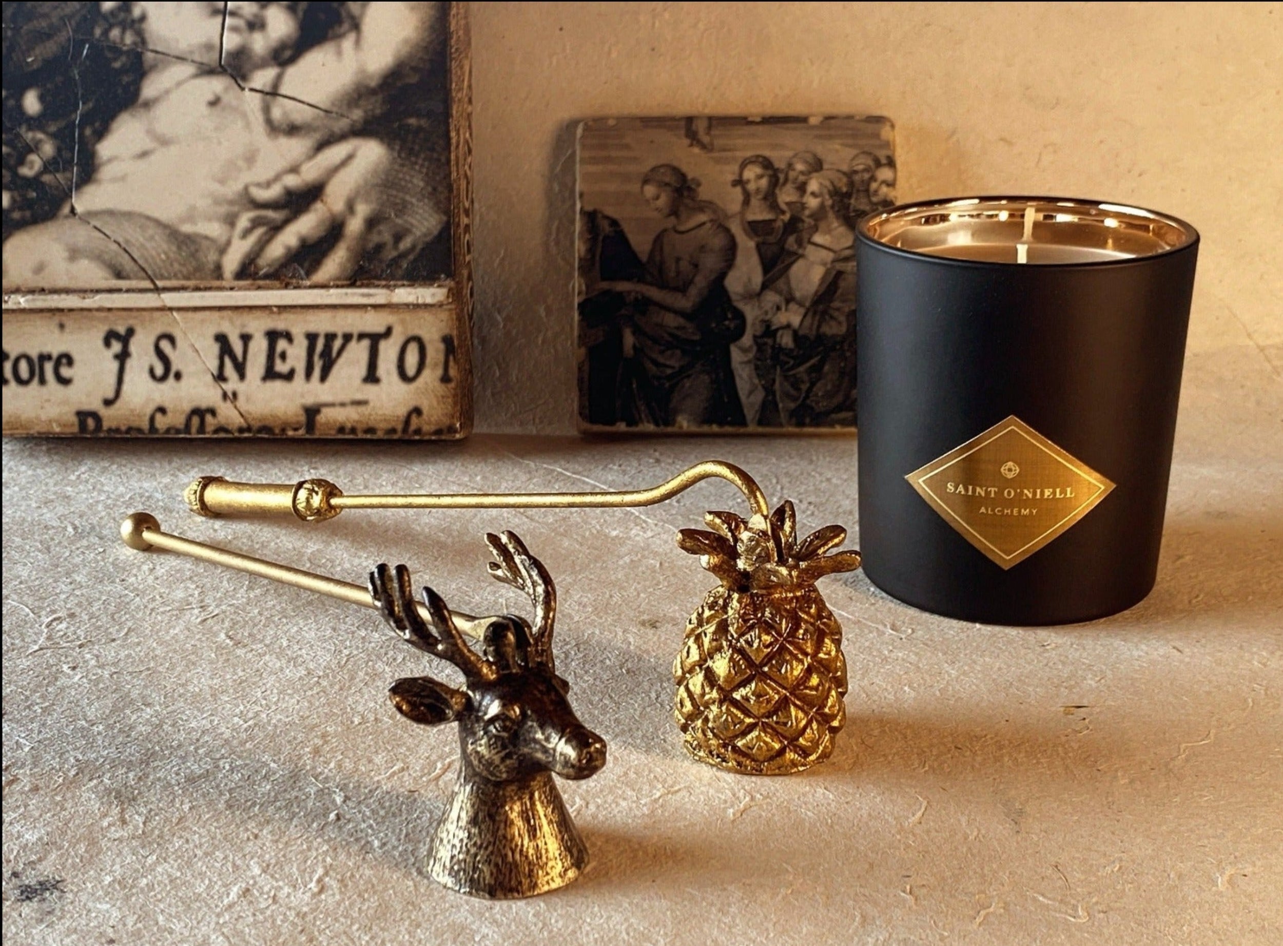 Saint O'Niell Alchemy's classic luxury scented candle vessel in black matte with gold metallic interior with two hand-forged candle snuffers in antique gold convey the elegant, natural aesthetic of the luxury brand.