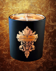 Saint O'Niell Alchemy The Queen's Beekeeper luxury candle in black vessel with gold metallic interior against a brown and gold damask background.  Aristocratic candle packaged in an artisan-designed gold foil stamped box.