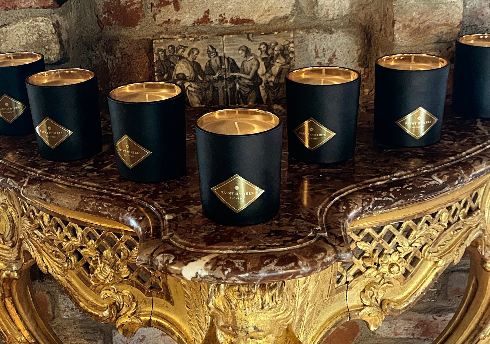 Saint O'Niell Alchemy luxury scented candle collection grouped atop an 18th c. French marble-topped demilune console table.